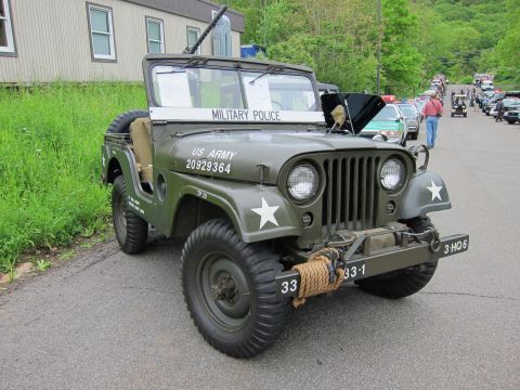 1991 Ford LTD Crown Victoria - olive-drab US Army Military Police jeep with white star markings, mounted machine gun and front winch at an outdoor show.