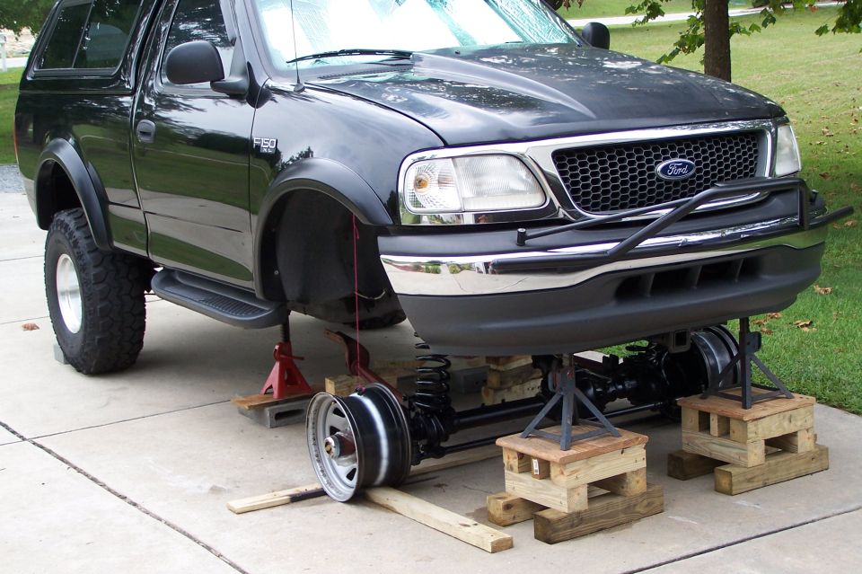 Black Ford F-150 on jack stands and wood blocks with front axle and springs exposed
