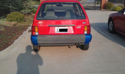 1991 Ford Festiva - The rear view of a red hatchback shows a two-tone bumper and a license plate.