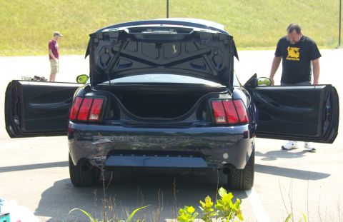 2007 Ford Mustang - A dark blue Ford Mustang is parked with its trunk and doors open, while two men stand around it.