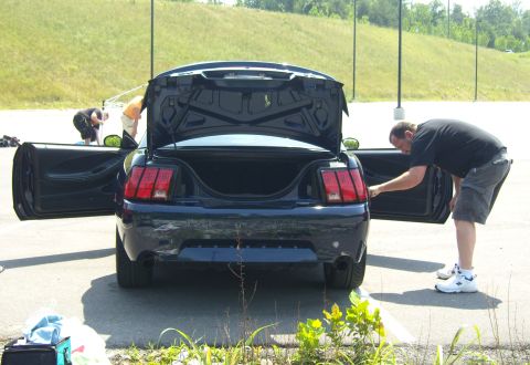 2007 Ford Mustang - A dark blue Ford Mustang is parked with its trunk and doors open, while a man attends to the driver's side.