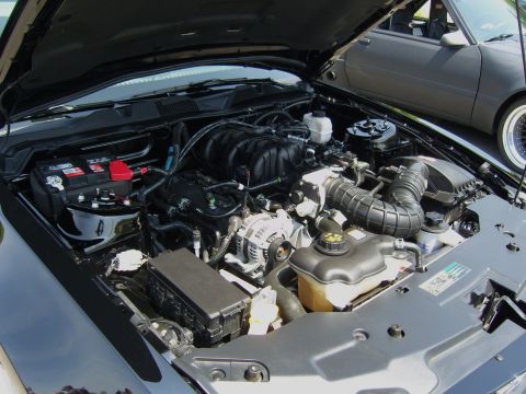 2007 Ford Mustang - The engine compartment of a black vehicle is shown with the hood open, revealing the engine and other components.