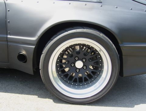2007 Ford Mustang - Close-up of a modified car's rear wheel and fender assembly, showing custom rivets and an exhaust outlet.