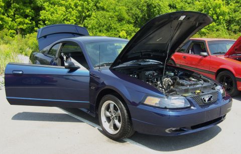 2007 Ford Mustang - Blue 2000 Ford Mustang GT with hood and driver door open, parked next to a red car.