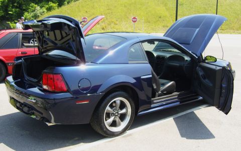 2007 Ford Mustang - A blue Ford Mustang is displayed with its hood, trunk, and driver's door open, parked next to a red vehicle.