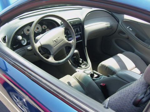 2007 Ford Mustang - The interior of a blue car, a steering wheel with a horse emblem and cloth seats.