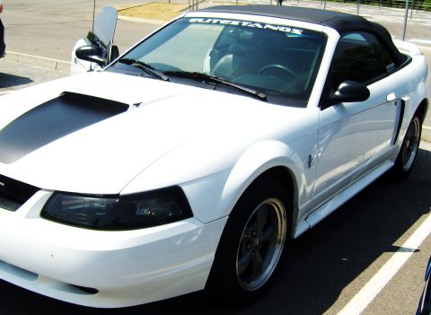 2007 Ford Mustang - A white convertible Mustang is parked in a lot, with its driver's side door open.