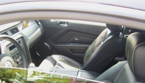 2007 Ford Mustang - The interior of a Ford Mustang features black leather seats with contrasting white stitching and a modern dashboard design.