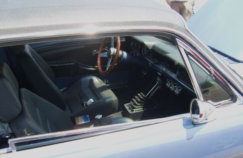 2007 Ford Mustang - Classic car interior with bucket seats, wood steering wheel, and manual transmission shifter.