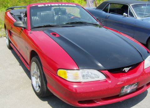 2007 Ford Mustang - Red convertible with a black hood and side scoops parked next to a blue coupe.