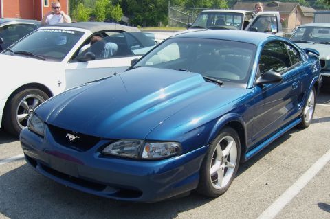 2007 Ford Mustang - Blue Ford Mustang coupe with aftermarket hood scoop, parked at a car meet.