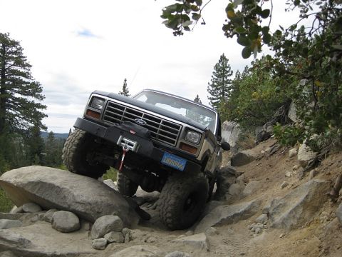 1985 Ford Bronco - A Ford Bronco tackles a challenging off-road course with large rocks and steep inclines.