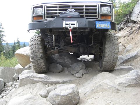 1985 Ford Bronco - This Ford Bronco navigates a rocky trail, its front grille and off-road capabilities.