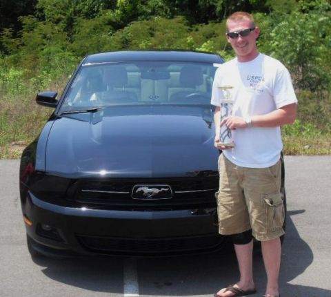 2007 Ford Mustang - A man stands proudly next to a black Ford Mustang, holding a trophy.