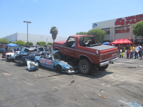 1978 Ford Bronco - A red lifted Ford Bronco is shown crushing a blue car in a demolition derby event.