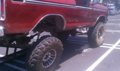 1978 Ford Bronco - This lifted 1978 Ford Bronco features large off-road tires and a bright red paint job, viewed from the side.