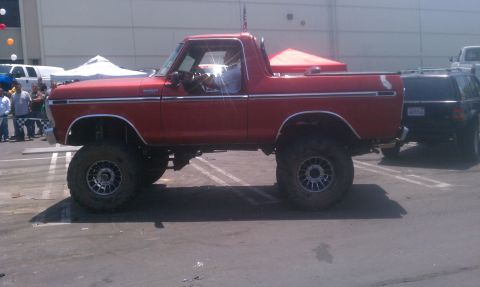 1978 Ford Bronco - A lifted red 1978 Ford Bronco is parked next to a black SUV.