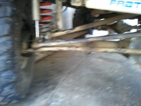 1978 Ford Bronco - Close-up view of the underbody suspension system, a tire and a shock absorber with red coil springs.