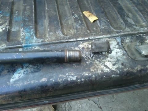 1978 Ford Bronco - A close-up of a metal shaft and a ribbed cap on a worn surface.