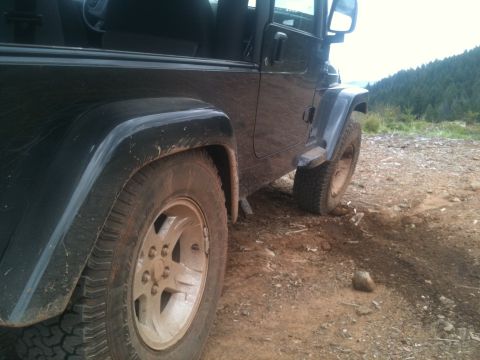 2005 Jeep Wrangler - A black 2005 Jeep Wrangler is parked on a dirt road with trees in the background.