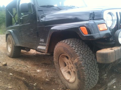 2005 Jeep Wrangler - A black Jeep Wrangler sits on a dirt road, its off-road tires ready for adventure.