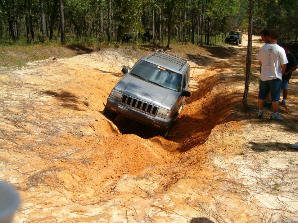 Silver Jeep Grand Cherokee navigating a rutted dirt path; another Jeep in background