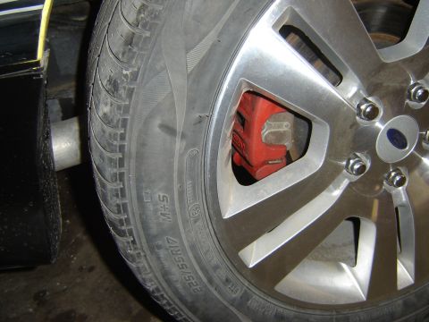 1979 Ford Mustang - A close-up view of a car's wheel, tire, and brake caliper, with an exhaust pipe in the background.