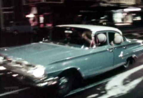 1969 Lincoln Continental - A light blue sedan from the 1960s is seen driving on a street at night.