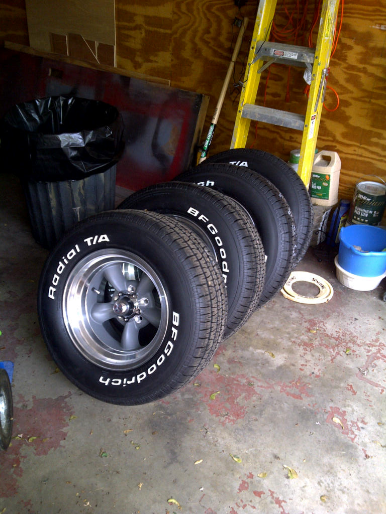Four BFGoodrich Radial T/A tires on aluminum wheels lined up in a garage