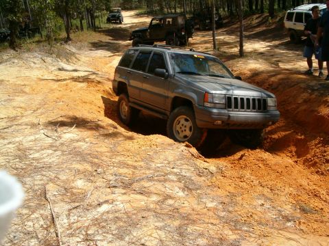 1991 Ford Bronco - Jeep Grand Cherokee tackles a challenging off-road course with other vehicles present.