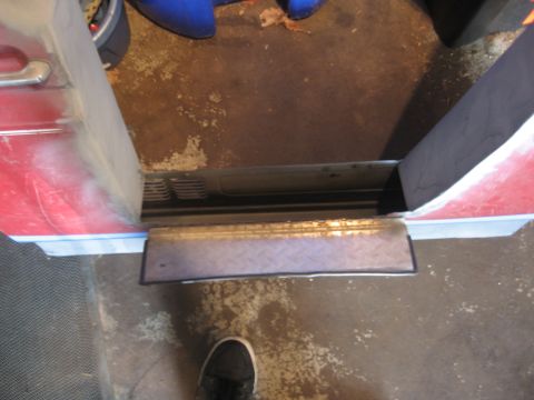 1996 Ford Bronco - Looking straight down at the bottom of a dark red truck door in a garage, with a diamond-plate step panel tacked to the lower edge and the…