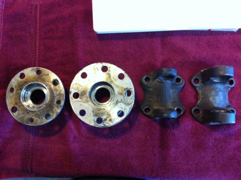 1987 Suzuki Samurai - Four automotive U-joint and flange components are laid out on a red cloth surface.