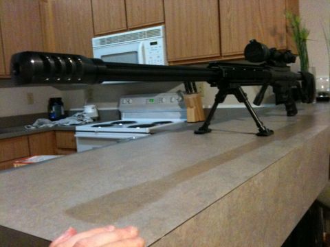 1996 Ford Bronco - A sniper rifle with a scope and bipod is placed on a kitchen counter, with a stove and microwave in the background.