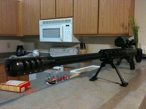 1996 Ford Bronco - A sniper rifle is placed on a kitchen counter, with a microwave and cabinets visible behind it.