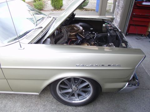 1965 Ford Galaxie - This 1965 Ford Galaxie 500 is shown with its hood open, revealing the engine bay and the prominent 'Galaxie 500' badging on the fender.