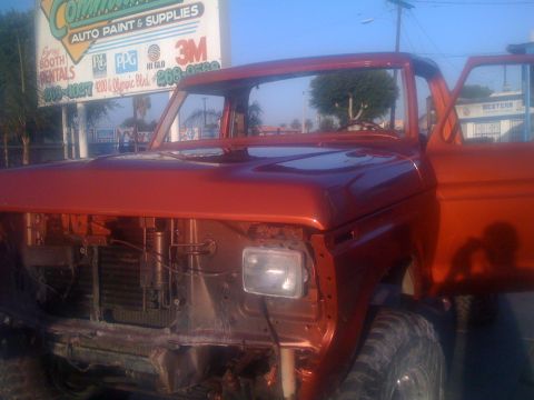 1978 Ford Bronco - This orange pickup truck, likely from the 1970s, is undergoing repairs at an auto paint and supplies shop.