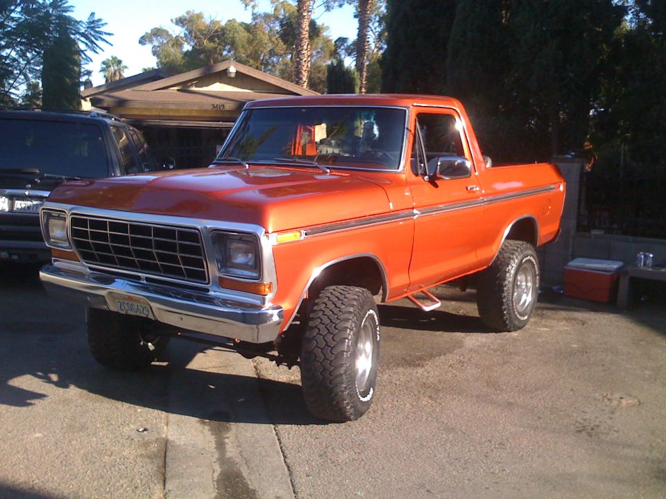 Orange pickup truck parked in driveway, another dark SUV to the left