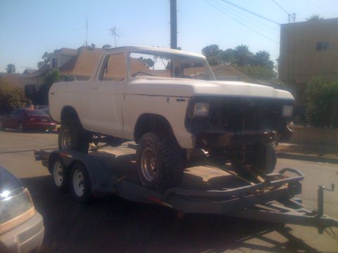 1978 Ford Bronco - A white 1978 Ford Bronco is transported on a trailer, missing its front bumper.