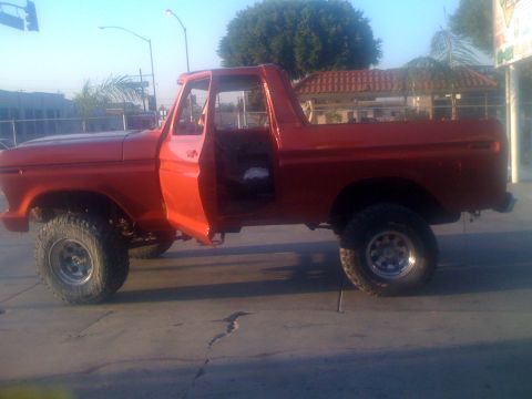 1978 Ford Bronco - This is a side view of a red pickup truck, likely from the 1970s, with its doors open.