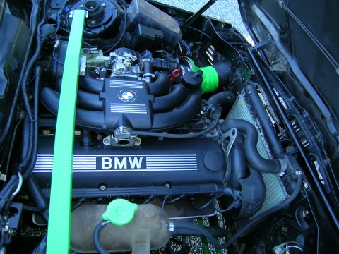 1982 BMW 3 Series - The engine bay of a BMW shows the valve cover with "BMW" text and a green strut bar.