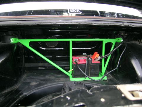 1982 BMW 3 Series - The trunk of a car shows a battery secured by a green strut bar, with a "LOCK" sticker visible on the rear window.