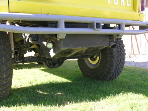 1966 Ford Bronco - Rear view of a yellow Ford truck, showing its axle, exhaust, and a heavy-duty bumper.