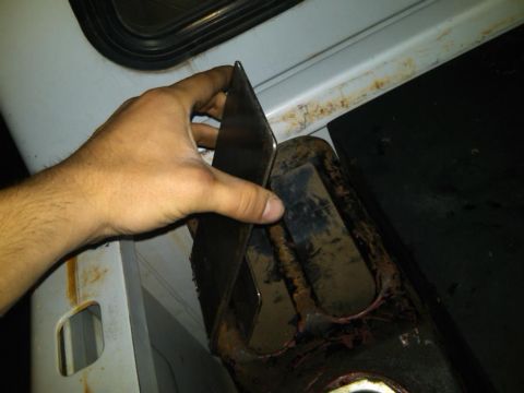 1995 Ford F-150 - A hand is shown holding a metal bracket near a rusty part of a vehicle.