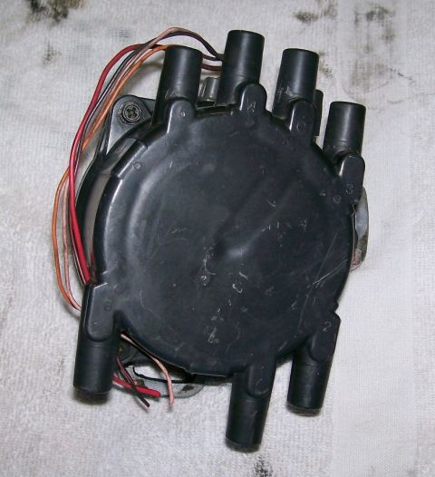 1995 Ford Probe - A black plastic distributor cap with wires is shown from a top-down perspective on a white cloth surface.