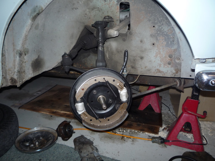 Drum brake backing plate with new shoes and wheel cylinders on a white car up on axle stands