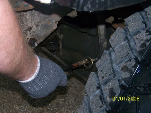 1989 Ford Bronco - A gloved hand is shown attaching a pin to the undercarriage of a vehicle, with a tire visible.