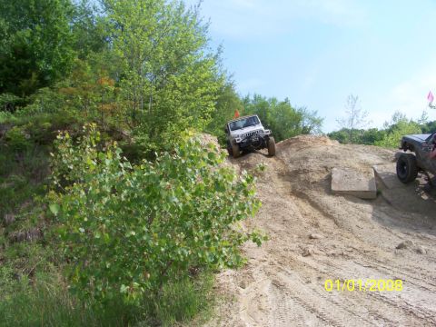 1989 Ford Bronco - Two off-road vehicles navigate a steep, sandy incline on a sunny day.