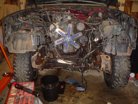1990 Ford Bronco - The engine bay of a vehicle is shown with exposed components and wiring, indicating it is undergoing maintenance or repair.