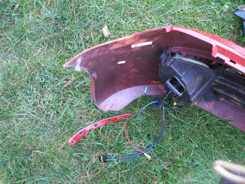 Red car bumper with exposed wiring and black housing