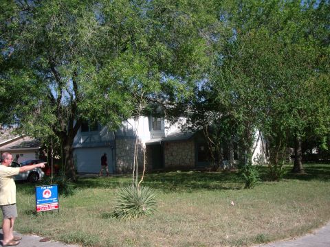 1983 Ford 427 - A man gestures towards a residential property with a "For Sale" sign prominently displayed on the lawn.
